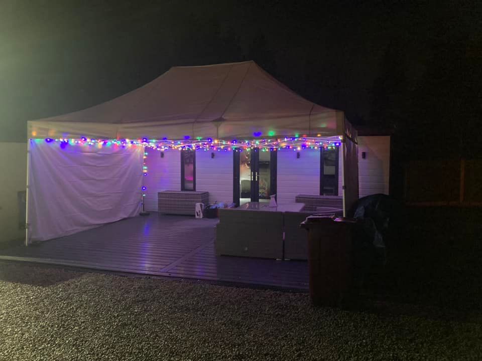 Gala Shade Pop Up Gazebo with outdoor furnishings and garden lights hanging from the frame