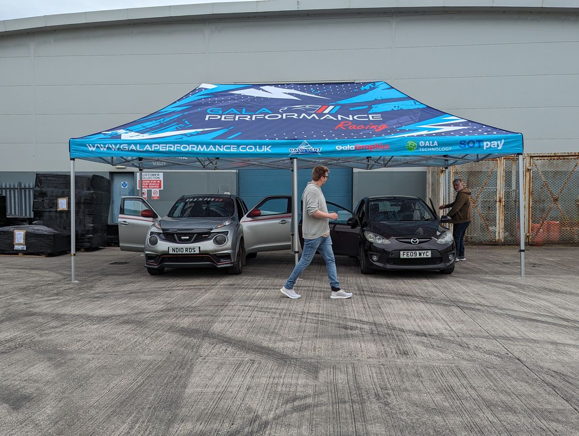 Pro 60 Gazebo with a custom printed canopy bearing Gala Performance branding sheltering two cars beneath it